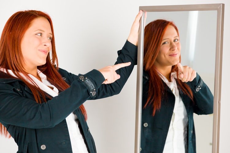 woman pointing at self in mirror